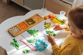 A little girl playing with Christmas tree from play dough for modeling with decorate from dried beans. Holiday Art Activity for Kids. Fine motor skills. Sensory play for toddlers.